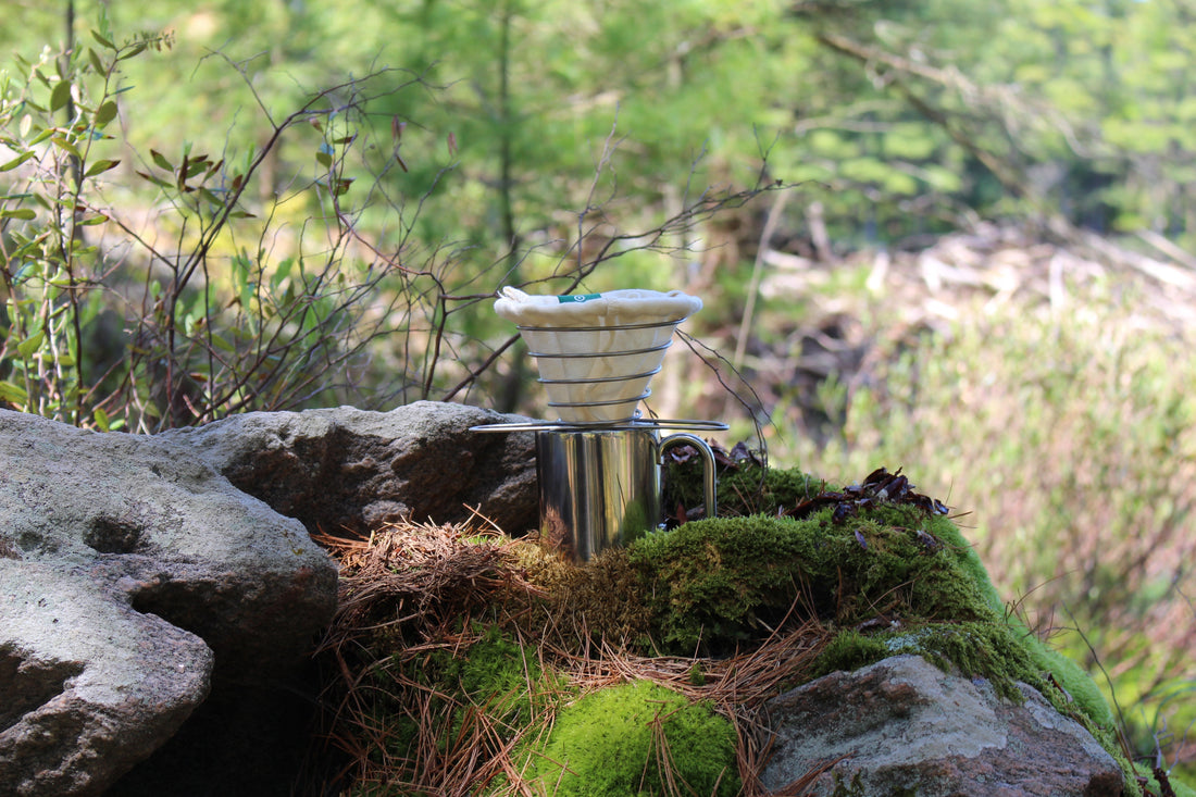 Reusable cotton coffee filter on a metal cup in a forest setting