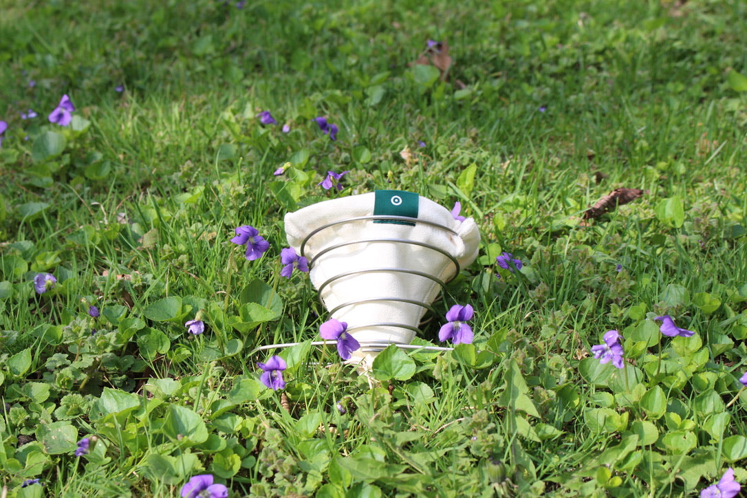 ACE Brewer organic cotton filter resting in grass among wild violets — showcasing natural materials and eco-conscious design.