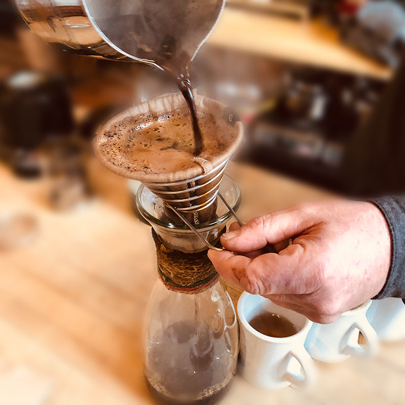 Hand brewing coffee by pouring hot water through the ACE Brewer filter in cafe