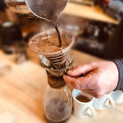 Hand brewing coffee by pouring hot water through the ACE Brewer filter in cafe